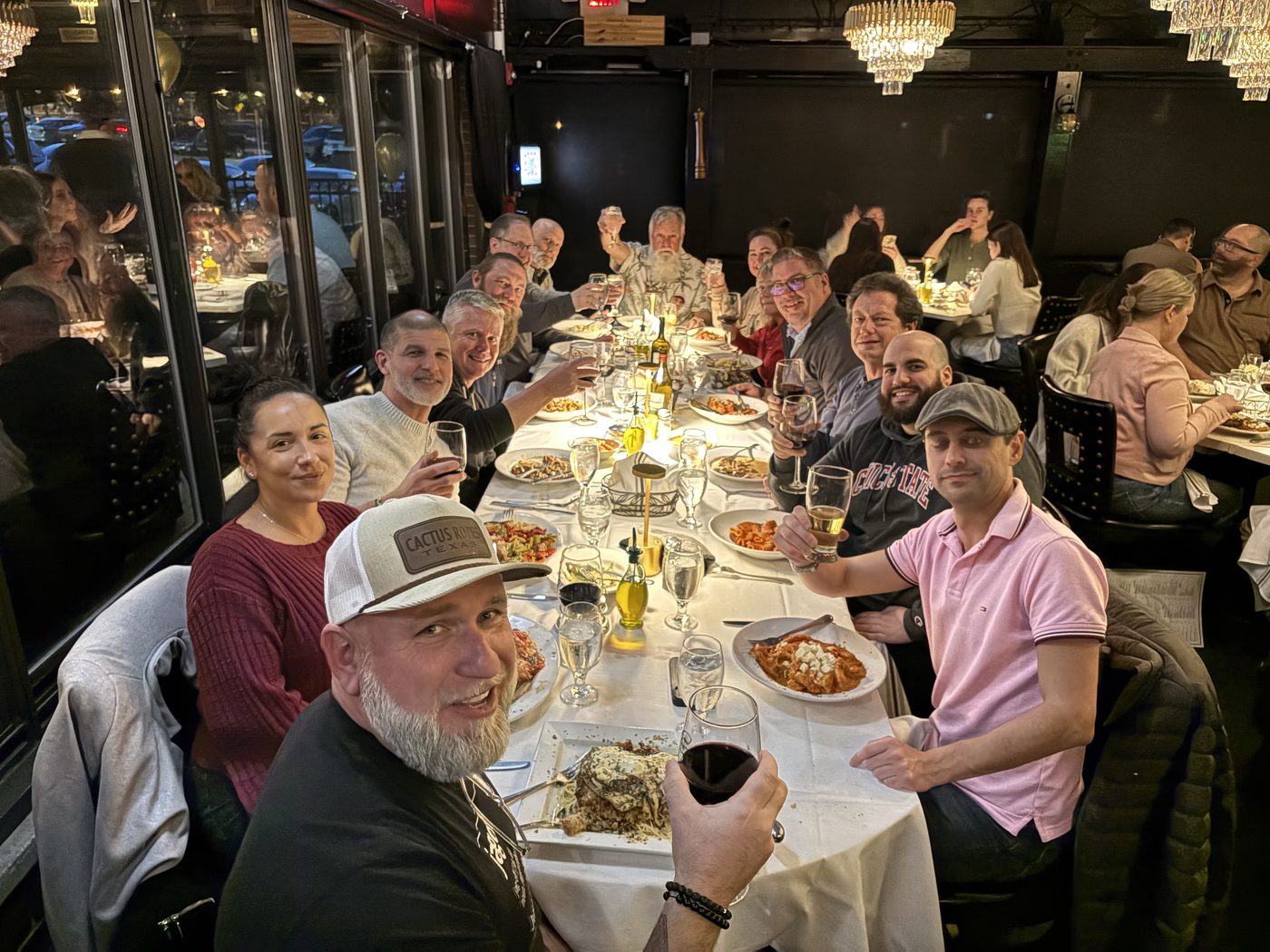 CMUG attendees gathered around a long dinner table, raising glasses after an event